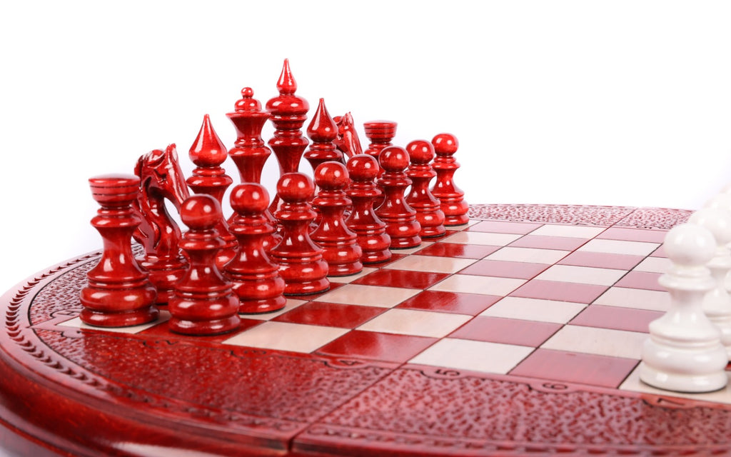 Red painted chess pieces at the edge of the round board with carved textured rim