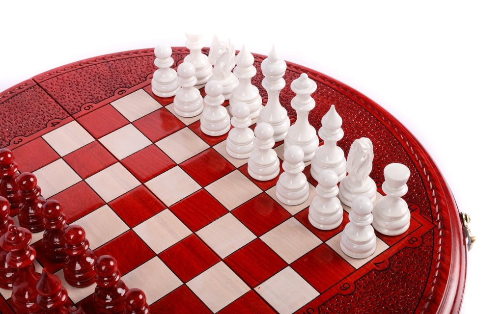 White hand-carved chess pieces on the red and cream squares of the round chess board