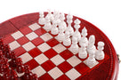 White hand-carved chess pieces on the red and cream squares of the round chess board