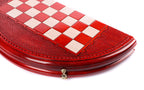 Close view of the red and cream checkered field and carved rim of the round board