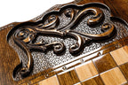 Carved scroll panel beside the chequerboard on the back cover, close-up