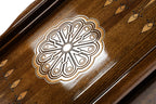 Eight-petal wheel ornament cut into the dark field of the open backgammon board