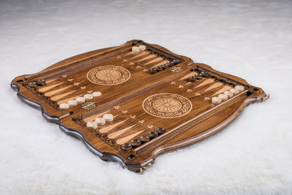 Wooden backgammon set laid open with checkers set up and a carved wheel on each half