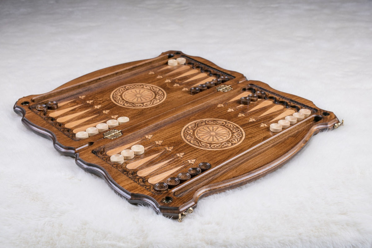 Wooden backgammon set laid open with checkers set up and a carved wheel on each half