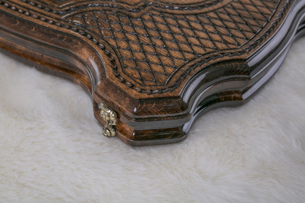 Close-up of the carved diamond lattice, rope border and curved edge of the board