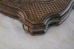 Close-up of the carved diamond lattice, rope border and curved edge of the board