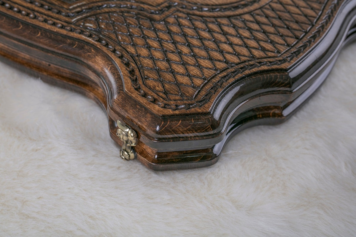 Close-up of the carved diamond lattice, rope border and curved edge of the board