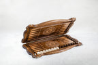 Wooden backgammon set opening, carved points, a wheel ornament and checkers in the side trays